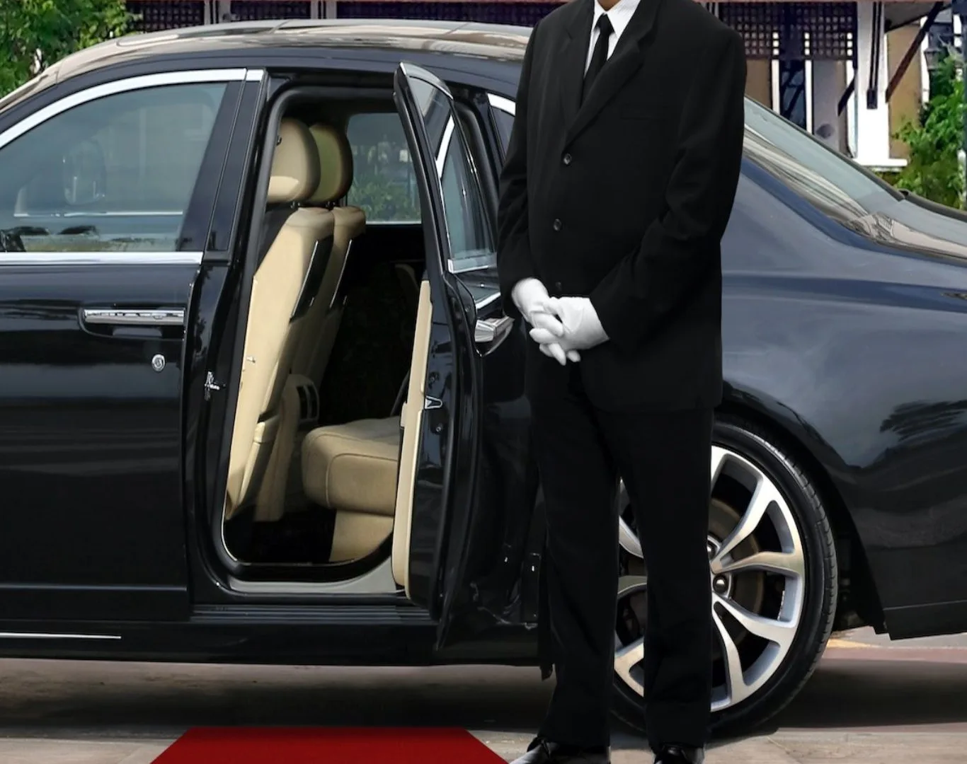 Professional chauffeur in a black suit and white gloves standing by an open luxury sedan door, representing premium Detroit Limo Service for airport and executive travel.
